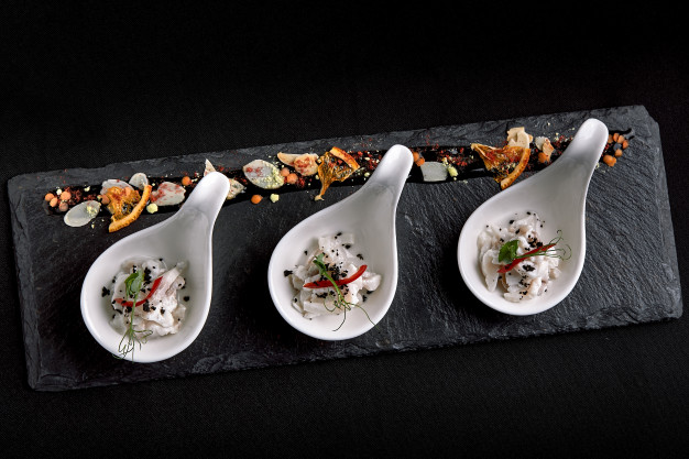 sea-bass-ceviche-mini-portions-served-beautiful-chinese-spoons-black-plateau-food-concept-catering_124865-1822