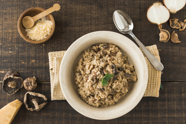 top-view-fungi-risotto-dish-with-ingredients-wooden-table_23-2147925973